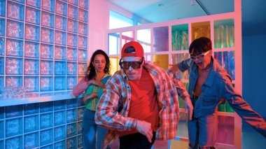 Değişik takımlarla dans ederken süslü gözlük takan yakışıklı hippi serbest stil müzikle mutlulukla dans ediyor. Beyaz hipster kulüpte parlak neon ışıkta sokak dansı yapıyor. Mutluluk.