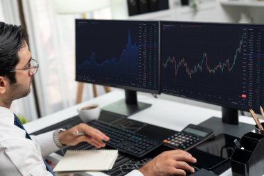 Akıllı tüccar işadamı, modern merkez ofisindeki araştırma pazarında en yüksek kârlı finansal teknolojiye yatırım yaparak bilgisayar üzerinde iki dinamik borsa yatırım ekranını analiz ediyor. Tahmin et..