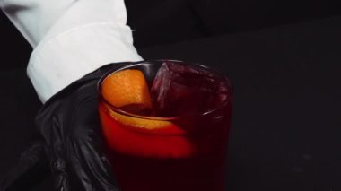Makrografi, Negroni kokteyli servis eden yetenekli bir barmenin elleri, siyah arka planlı canlı taze portakal dilimleriyle süslenmiş. Her yakın çekim kokteyl hazırlığını yakalar. Geliştirilebilir.