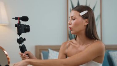 Sosyal medya için güzellik ve kozmetik video içeriği hazırlayan genç bir kadın. Güzellik blogcusu kameraya gülümserken seyircilere ve takipçilere güzellik bakımını gösteriyor. Düzenle