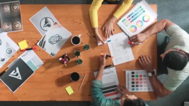 Proje yöneticisi renk paletleri seçerken tasarımcının tablete baktığı yukarıdan aşağıya hava görüntüsü. Profesyonel grafik tasarımının en üst görüntüsü ve logoya bakın. Yetenekli ekip grafikleri seçiyor. Sempozyum.