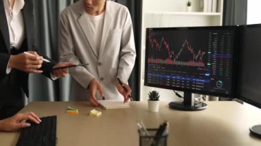 Menkul kıymetler borsası pazarlamasını inceleyen borsa yatırımcıları, zarar ve kazanç için mum bar fiyatlarını analiz eden monitörlere bakıyor. Filizlenen