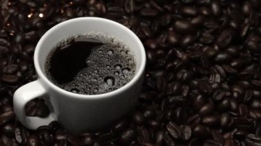 Kahve ya da kahve çekirdekli espresso manzarası. Taze kavrulmuş kahve çekirdeğini yakın çekimde ahşap masanın etrafına bir fincan americano ve aromatik akarsu ve tohum dumanı serpin. Geliştirilebilir.