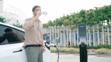 Yavaş çekim adamı, EV şarj aletini şehrin alışveriş merkezinin otoparkındaki şarj istasyonundan şarj etmek için kullandı. Sürdürülebilir şehirde EV aracı tarafından şarj edilebilir enerji olarak kullanıldı.