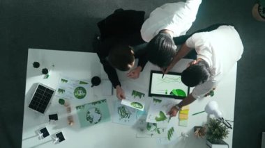 Yenilenebilir enerji hakkında tartışan iş ekibinin aşağı görüşü. Masada dizüstü bilgisayar kullanırken sıfır atık hakkında plan yapmak için birlikte çalışan yetenekli iş adamlarının hava görüşü. Hizalama.