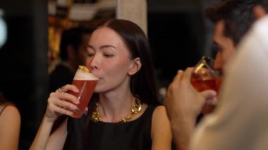 Paloma kokteyli içen güzel bir kadın, gece kulübü partisinin olduğu lüks bir barda ellerinde eski moda, zevkli bir içki olan akıllı bir çiftle konuşuyor. Vinosity.