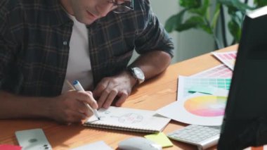 Akıllı tasarımcının renkli paletlerden renk seçmesine yardım ederken yukarıdan aşağı görünümü. Dizüstü bilgisayardan logoya bakarken birlikte çalışan ve planlayan iş adamlarının hava görüntüsü. Sempozyum.