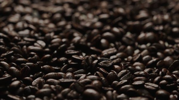 Close up of fresh brown coffee bean with roasted smoke from pile of coffee beans. Macrography of hot coffee seed with fragrant and scented hot smoke come from pile of bean. Top down view. Comestible.
