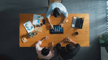 İş adamının üst düzey görüşü, bir grup akıllı yatırımcıya finansal grafik sunuyor. Profesyonel erkek lider grafiği analiz eder ve pazarlama fikrini toplantı masasında tablet kullanarak açıklar. Cemaat.