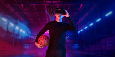 Basketball player holding basketball hologram at futuristic sport arena. Energetic athlete or sport person practicing basketball skill by using augmented reality technology. Innovation. Ingenuity. clipart