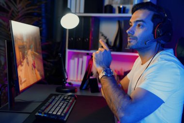 Akıllı oyun flaması dijital neon ışıklı siber odada kulaklık takarak bilgisayar ekranında çoklu ya da tek oyuncuyla çevrimiçi atış oyunu oynayan bir savaş takımı ile oynamaktan zevk alır. Tahmin et..