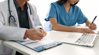 Hastane masasında birlikte çalışan ve tıbbi tedavi planlayan çeşitli profesyonel sağlık görevlileri. Takım çalışması başarılı hastalıklara ve hastalıklara yol açar. Ağır çekim. Katı.