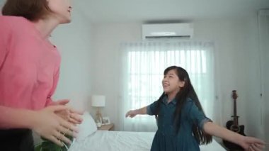 Yatak odasında Asyalı kızıyla müzik eşliğinde dans eden mutlu çekici anne. Beyaz anne dans eder ya da egzersiz yapar. Bu arada tatlı çocuk da müzik eşliğinde yatağa atlar. Aile eğlence konsepti. Pedagoji.