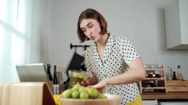 Kafkaseli anne kahvaltıda sebze pişirirken mutlu anne de modern mutfakta salata için taze malzemeler hazırlıyor. Hizmetçi sağlıklı yemek pişiriyor. Dikkat konsepti. Pedagoji.