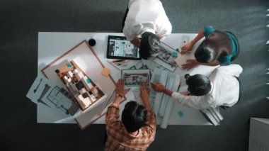 İç mimar tasarımcı dış tasarım hakkında konuşurken ve tartışırken mimar mühendis ekibinin yapışkan notlar yazıp ev modeline not yapıştırdığı yukarıdan aşağıya hava görüntüsü. Hizalama.