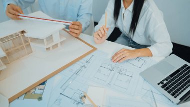 Profesyonel mühendis ev modelini tartartarken, yetenekli tasarımcı da planına yazar. Birlikte çalışmak, işbirliği, işbirliği. Yaratıcı tasarım ve takım çalışması konsepti. - Yakın çekim. Tertemiz.