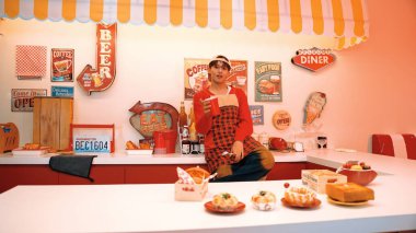 Profesyonel Asyalı restoran işçisi içki hazırlar ve yemek barının arkasında durur. Kırmızı gömlekli ve kırmızı önlüklü mutlu garson kameraya bakarken serbest stil müziğe geçiyor. Çılgın dans. Mutluluk.