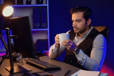 Gülümseyen zeki işadamı, elinde kahve fincanı olan satış ekibiyle buluşuyor ve geceleri Mor Neon Light Home Office 'deki bilgisayar ekranında ürün hedef pazarını araştırıyor. Tahmin et..