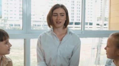 Farklı öğrencilerle çevrili yerde birlikte otururken, zeki beyaz bir öğretmen ders veriyor. Çok kültürlü bir öğrenciyle oynayan profesyonel bir eğitmen. Yaratıcı eğitim konsepti. Etkinlik.