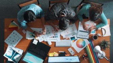 Tasarımcı fikirleri yazarken proje yöneticisinin yukarıdan aşağıya bakan görüntüsü. Akıllı iş adamları logo tasarımı fikrini açıklarken tasarımcılar palete bakarken temayı seçiyorlar. Sempozyum.