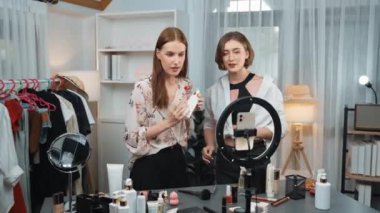 İki kadın nüfuzlu partner sosyal medya veya blog için canlı yayın yapan video klip inceleme derisi çekiyorlar. Kozmetik stüdyosu ışıklandırması olan genç bir kız pazarlama oturumu çevrimiçi yayın yapıyor.