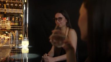 Parlak gece partisinde lüks bir gece kulübünde özel içkide gözlüklü güzel bir kadının portresi. Barda oturmuş, barmen ve arkadaşlarıyla atmosfer partisi saatleri hakkında konuşuyor. Vinosity.