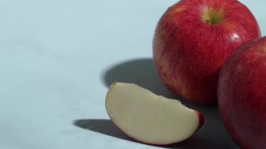 Mavi arka planda dilimlenmiş kırmızı elmaları kapatın. Elma dilimlenmiş makarnanın mavi arka planında elmacı ve suyun dökülmesi ve el sallaması. Sağlıklı beslenme ve taze üretim kavramı. Pabulum.