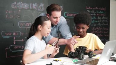 Kafkas öğretmeni dizüstü bilgisayarı işaret ederken araba modelleme sistemini kara tahtada kodlama veya programlama koduyla açıklıyor. Robot inşaatını öğrenen çeşitli öğrencileriniz kutlu olsun. Öğretim