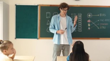 Matematik formülü veya teorisi ile karatahtanın önünde dururken sınıfın etrafına bakan profesyonel akıl hocası. Çeşitli ilköğretim öğrencileri matematik dersinde öğreniyor, çalışıyor ve oturuyor. Pedagoji.