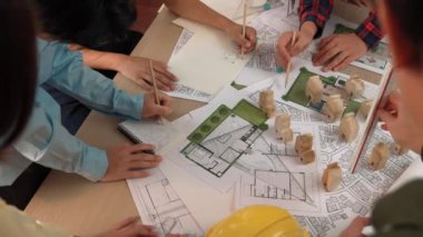 Mimari belge, ölçüm aracı ve ahşap blokların modern ofiste etrafa saçıldığı bir masa üzerinde yapı inşaatı ile ilgili mimar ve güvenlik mühendisi tartışması. Tanımlama.