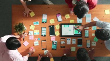 Ux ui tasarımını renkli yapışkan nota üzerine yazmak için birlikte çalışan geliştirici ekibinin üst görüşü. Tablet 'te kablo prototipi inceleyen ve yazılım tasarlayan bir grup programcı. Cemaat.