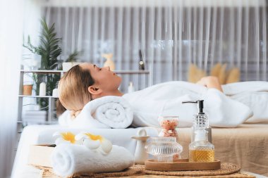 Aromatherapy massage on daylight ambiance or spa salon composition setup with focus decor and spa accessories on blur woman enjoying blissful aroma spa massage in resort or hotel background. Quiescent clipart