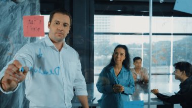Yetenekli işadamı, cam duvara renkli yapışkan notlar yapıştırarak proje yöneticisine pazarlama fikrini sundu. Proje yöneticisi yatırımcıya projeyi gösteriyor, anlatıyor, gösteriyor. Yönlendirici.