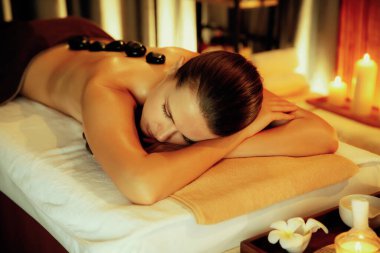 Lüks tatil köyündeki kaplıcalarda sıcak taş masajı, sıcak mum ışığı, spa bazalt taşı masajının keyfini çıkaran mutlu kadın müşteriler, rahatlatıcı bir sıcaklıkla vücudun üzerinde süzülüyorlar. Sessiz.