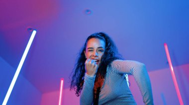 Latin dansçıların kameraya bakıp şehrin pop müziğiyle dans ettiği düşük açılı kamera. Profesyonel çekici hipster, mor veya neon ışıklı hip hop şarkısına geçiyor. Şık bir kumaş. Mutluluk.