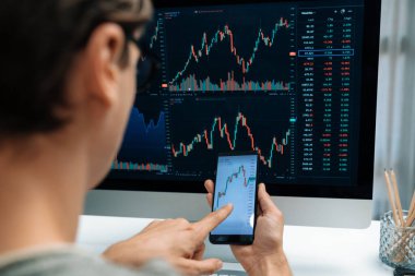 Akıllı borsa yatırımcıları ekranda akıllı telefon ile piyasa borsasını işaret ederek dizüstü bilgisayarın yanı sıra en yüksek dinamik yatırım oranını göstererek, modern işyerindeki veri planlamasına odaklanıyorlar. Bireysel.