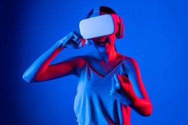 VR kulaklık takan zeki bir kadın metaevrene bağlanıyor, gelecekteki siber uzay topluluğu teknolojisi. Duruş kontrol oyuncusunu yumruklayan zarif bir kadın dövüş oyunları oynuyor. Halüsinasyon.