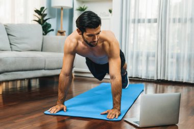 Atletik ve sporcu adam, evdeki fiziğe ve sağlıklı spor yaşam tarzına uygun vücut egzersizi sırasında spor minderinde şınav çekiyor. Gaiety evde egzersiz eğitimi.