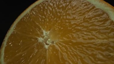 Portakal diliminin bir makrografi görüntüsü, parlak, izole edilmiş bir arkaplan üzerine yerleştirilmiş, narenciye cazibesinin görsel bir başyapıtı olarak gözler önüne seriliyor. Siyah arkaplanlı bir dilim portakal. Geliştirilebilir.
