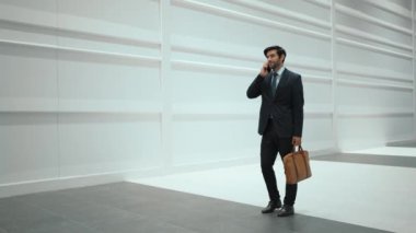 Yöneticiyle plan ve kamera hakkında konuşurken yetenekli bir yönetici yürüyor. Erkek lider, beyaz arka planda dururken satış hakkında konuşmak ve rapor vermek için iş ekibini arıyor. Sevinçli..