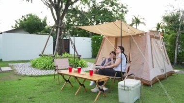 Aile hep birlikte bahçedeki kampta oturup yemek yiyor. Ebeveynler, genç nesil arasında iletişim kurmak ve zaman geçirmek için açık hava kamp faaliyetlerini kullanıyorlar. Uyumsuzluk.