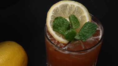 Macrography,of a Tequila Sunrise cocktail adorned with a slice of lemon and fresh mint leave, set against a dramatic black background. Close-up shot captures the vivid colors of cocktail. Comestible. clipart