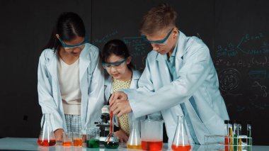 Zeki kız deney yapmak için heyecanlanan çeşitli öğrenciler iken beher kabına renkli solüsyon döker. Profesyonel bilim adamı kimyasal teoriyle kara tahtada deney yapmaya hazırlanıyor. Öğretim.