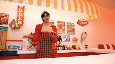 Profesyonel Asyalı restoran işçisi yemek hazırlar ve yemek barının arkasında durur. Kırmızı gömlekli ve kırmızı önlüklü mutlu garson kameraya bakarken serbest stil müziğe geçiyor. Çılgın dans. Mutluluk.