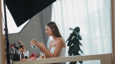 Sosyal medya için güzellik ve kozmetik video içeriği hazırlayan genç bir kadın. Güzellik blogcusu kameraya gülümserken seyircilere ve takipçilere güzellik bakımını gösteriyor. Düzenle