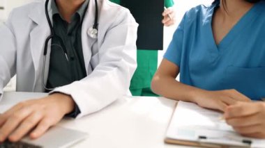 Hastane masasında birlikte çalışan ve tıbbi tedavi planlayan çeşitli profesyonel sağlık görevlileri. Takım çalışması başarılı hastalıklara ve hastalıklara yol açar. Ağır çekim. Katı.