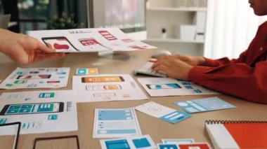 Mobil uygulama için kullanıcı arayüzü prototipini ofis çalışanlarına sunan harika bir şirket çalışanı. UX UI tasarımcısı kağıt üzerinde simge tasarımının işlevini açıklıyor. Sinerjik