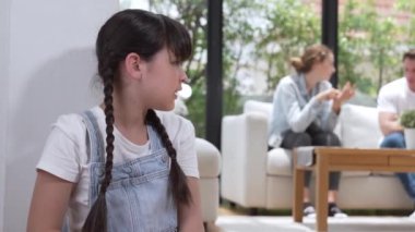 Stresli ve mutsuz genç kız köşeye kıvrılıp kulaklarını kapatarak arka planda ebeveyninin tartışmasını engelliyor. Evde aile içi şiddet ve travmatik çocukluk depresyona dönüşür. Titiz