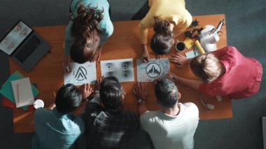 Akıllı iş adamlarının üst görünümü toplantı masasına grafik logo koydu ve fikri açıklarken tasarım yapmaya başladı. Konsept sanatından bahsederken proje yöneticisinin hava görüntüsü ve mevcut plan. Sempozyum.