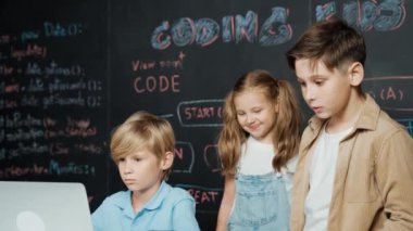 Çocuğun dizüstü bilgisayar mühendisliği kodunu ve yazım programını kullanırken bir grup zeki öğrencinin etrafı STEM teknoloji sınıfında arkadaşlarıyla çevriliyken karatahtaya oturması. Etkinlik.